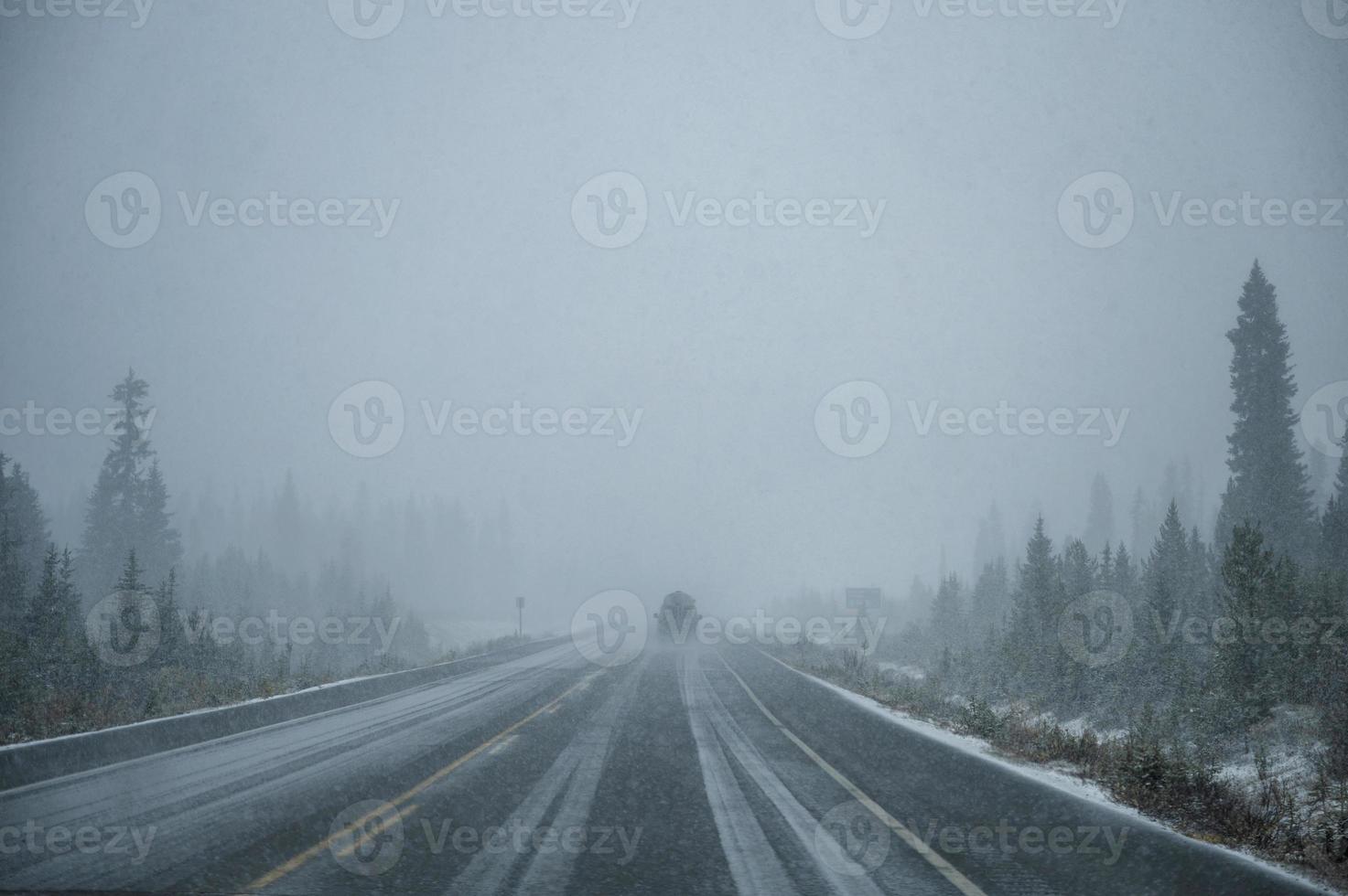 bil kör i tung snö på motorväg i tallskog vid banff nationalpark foto