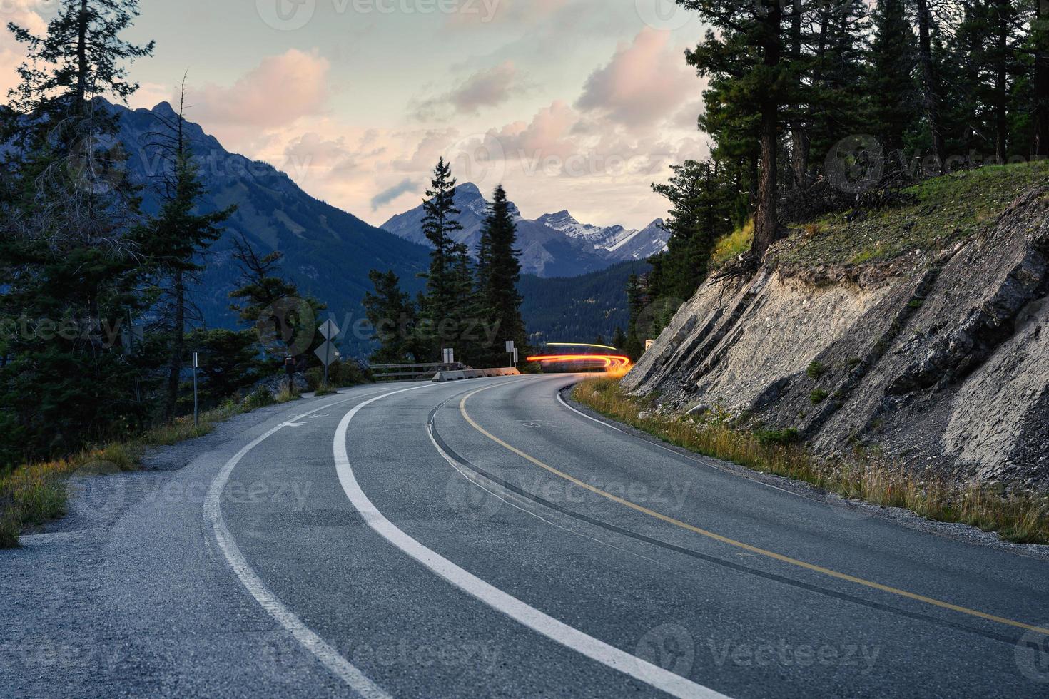 lätt bil på motorväg med steniga berg i banff nationalpark foto