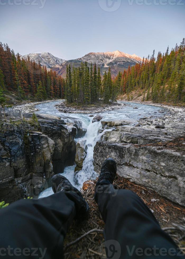 benresenär sitter och sträcker sig på sunwapta -fall i isfältparway vid jasper nationalpark foto