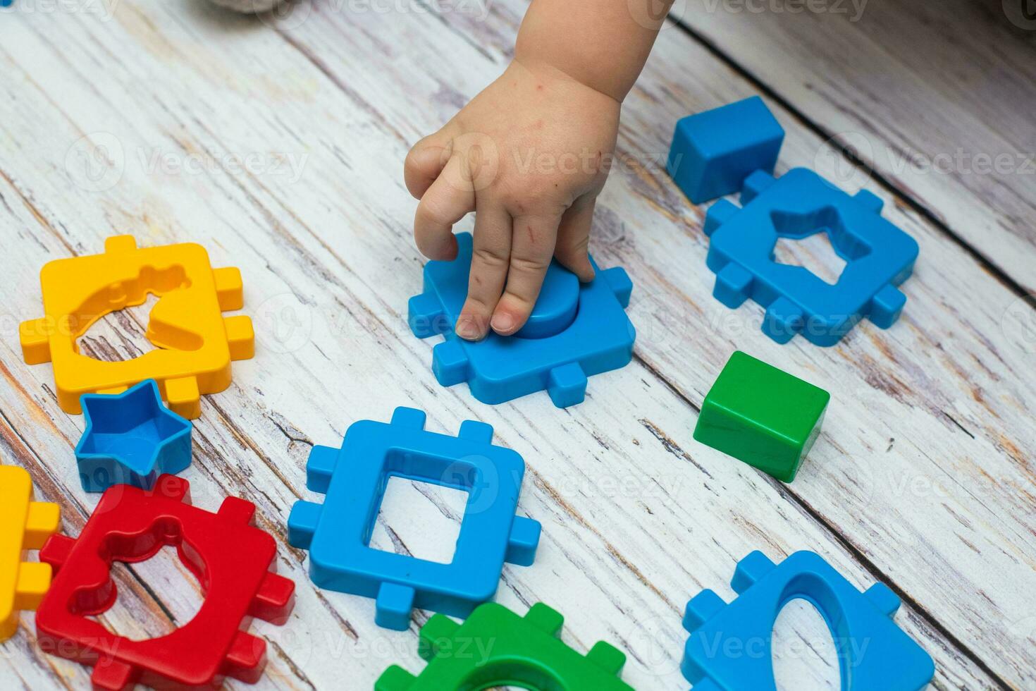 hand av barn sätta grön verkan figur i bebis block form sorterare leksak. pedagogisk sortering matchande leksak för småbarn foto