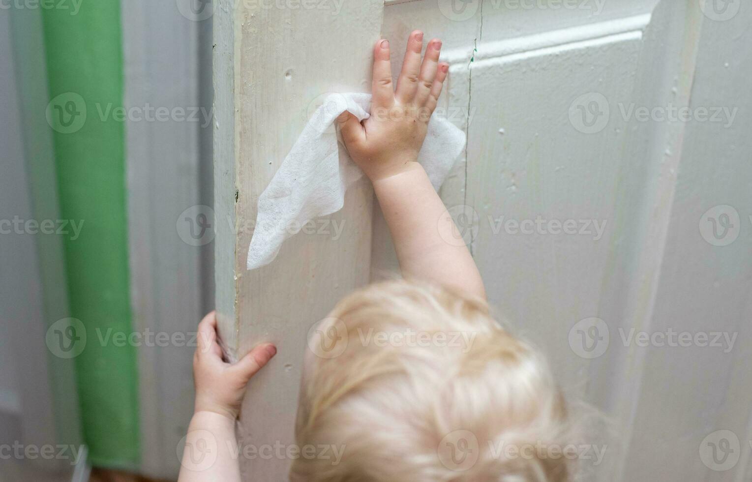 bebis tvättar de årgång gammal dörrar med servett under en viral epidemi. rengöring Hem. undervisning barn till vara självständig. använda sig av av våt våtservetter i varje dag liv foto