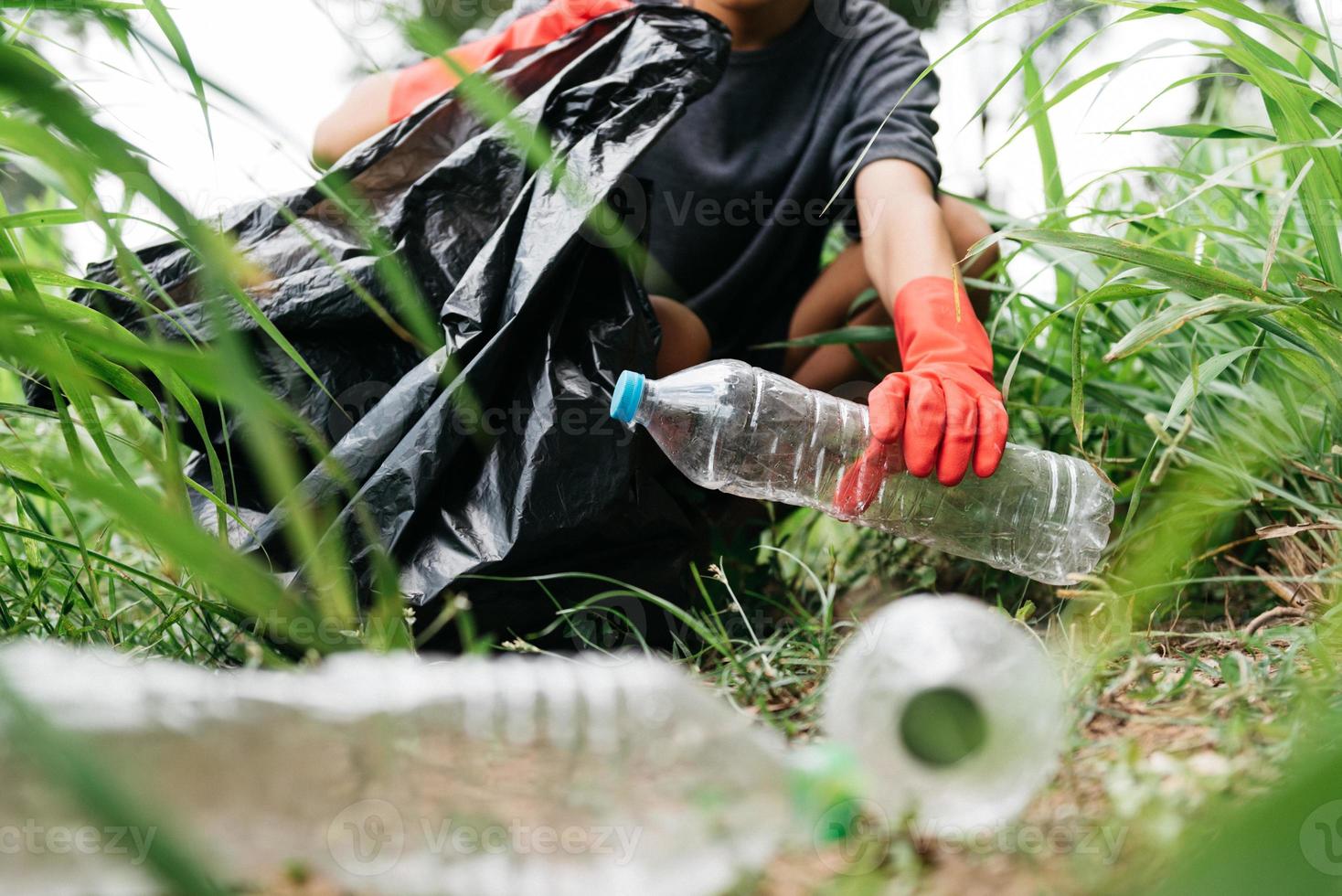 pojke man hand plocka upp plastflaska i skogen. miljö koncept. foto