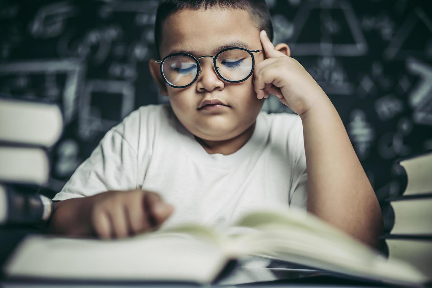 pojkar med glasögon skriver böcker och tänker i klassrummet foto