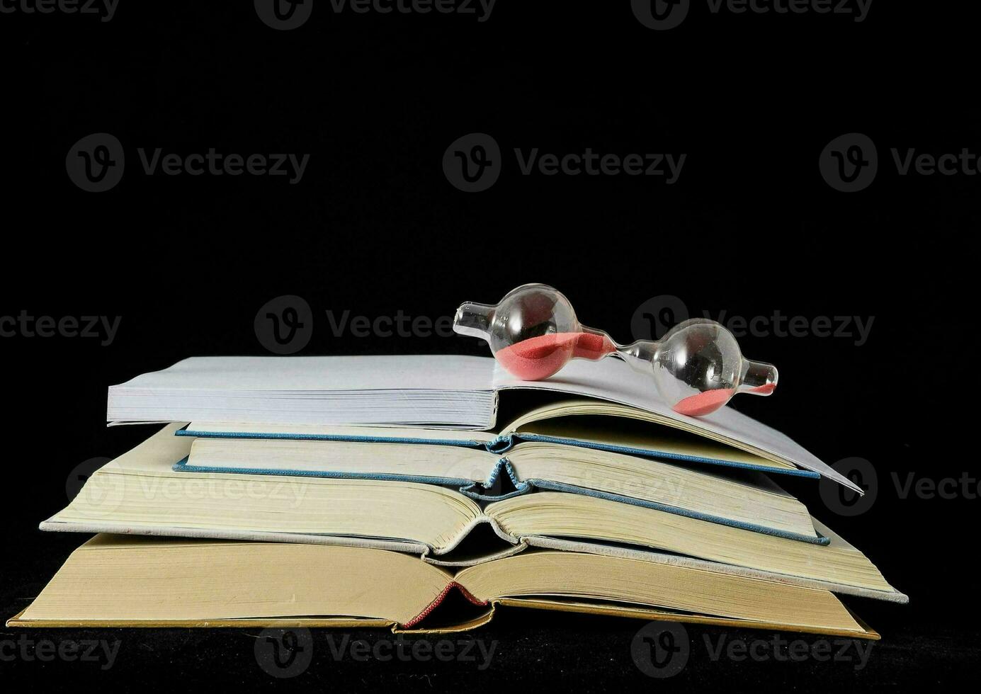 en stack av böcker med ett timglas på topp foto
