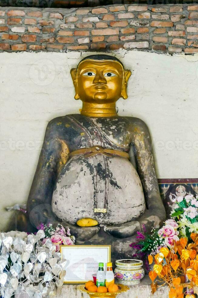 en stor gyllene buddha staty i främre av en vägg foto