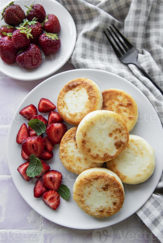 keso pannkakor, ricotta fritters på keramisk tallrik med färsk jordgubbe. foto