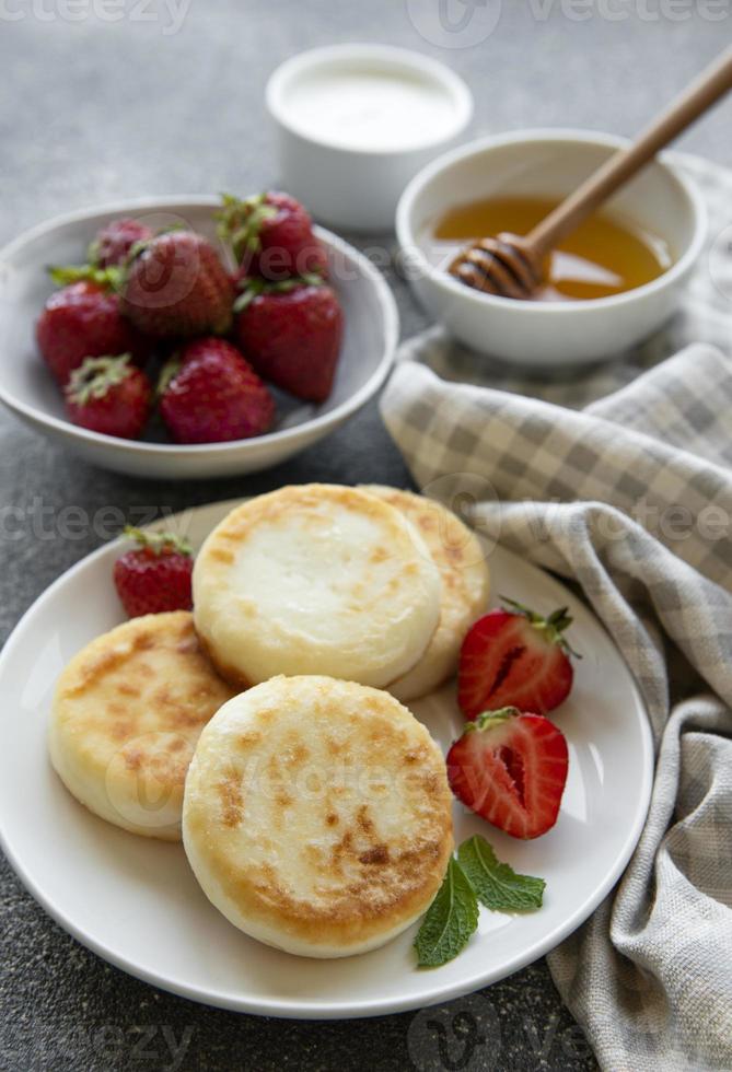 keso pannkakor, ricotta fritters på keramisk tallrik med färsk jordgubbe. foto