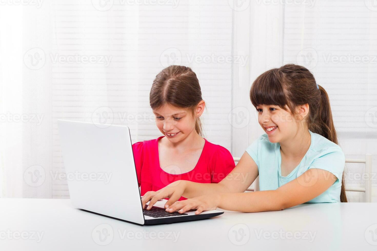 söt liten flickor är Sammanträde och använder sig av bärbar dator. foto