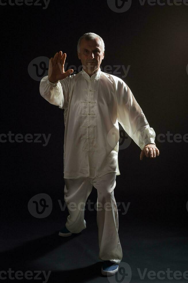 senior man åtnjuter övning tai chi inomhus- foto