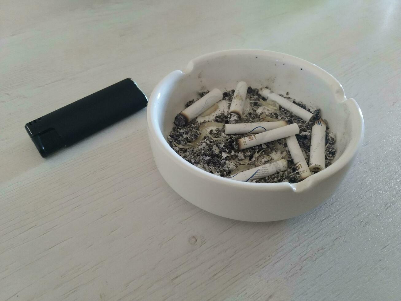 cigarett butts i askkopp på trä- tabell. foto