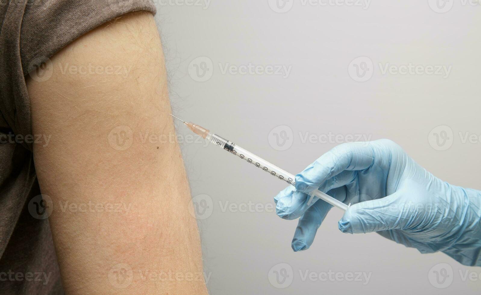 de hand av en para gör ett injektion av en vaccin till ett osynlig person. hälsa begrepp. skydd mot coronavirus foto