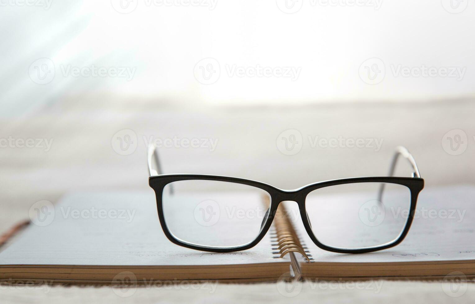 bild av ett öppen anteckningsbok placerad i säng med glasögon på de topp och en fönster i de bakgrund.suddig bakgrund. hög kvalitet Foto