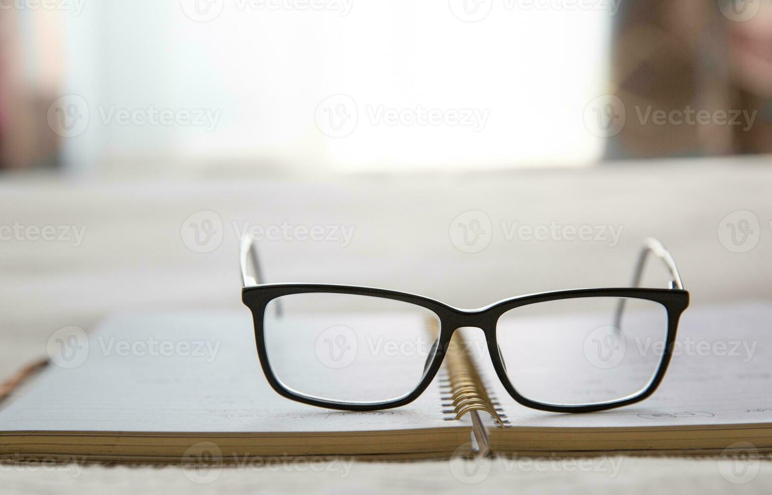 bild av ett öppen anteckningsbok placerad i säng med glasögon på de topp och en fönster i de bakgrund.suddig bakgrund. hög kvalitet Foto