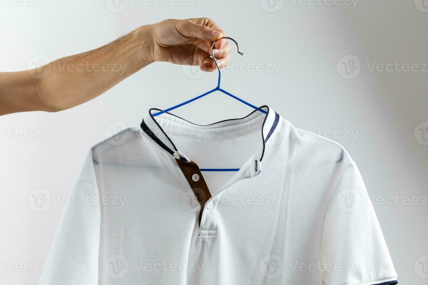 vit skjorta på en galge på en vit bakgrund foto
