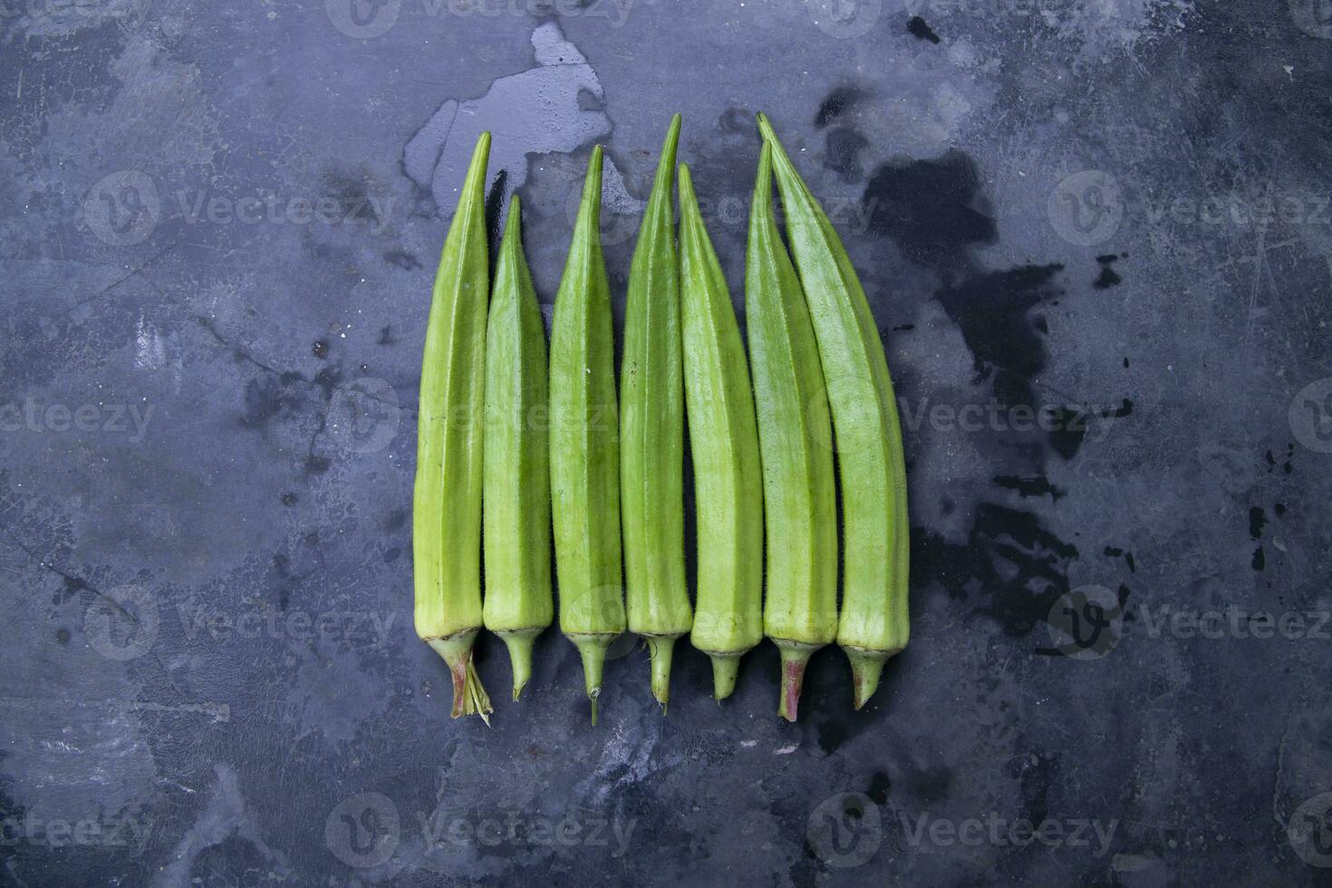 färsk organisk grönsaker damens finger eller okra på de mörk betong golv foto