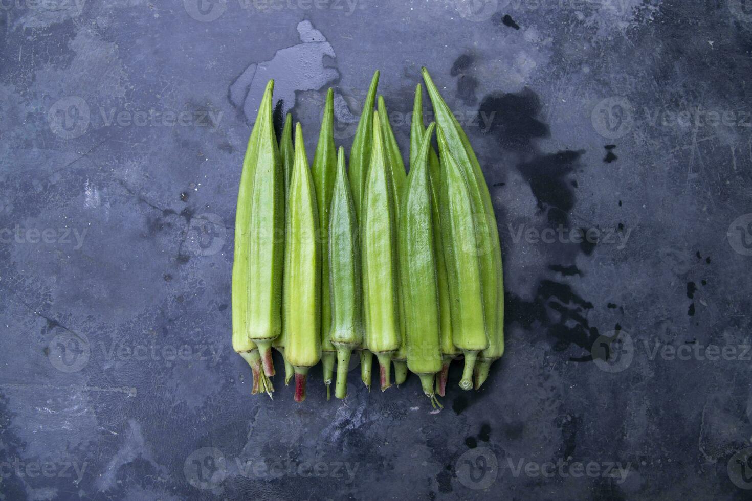 färsk organisk grönsaker damens finger eller okra på de mörk betong golv foto