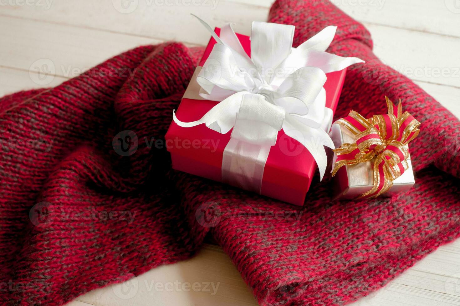gåva lådor på stickat scarf en röd scarf på vit trä- tabell topp se. värma ny år. platt lägga, topp se. foto