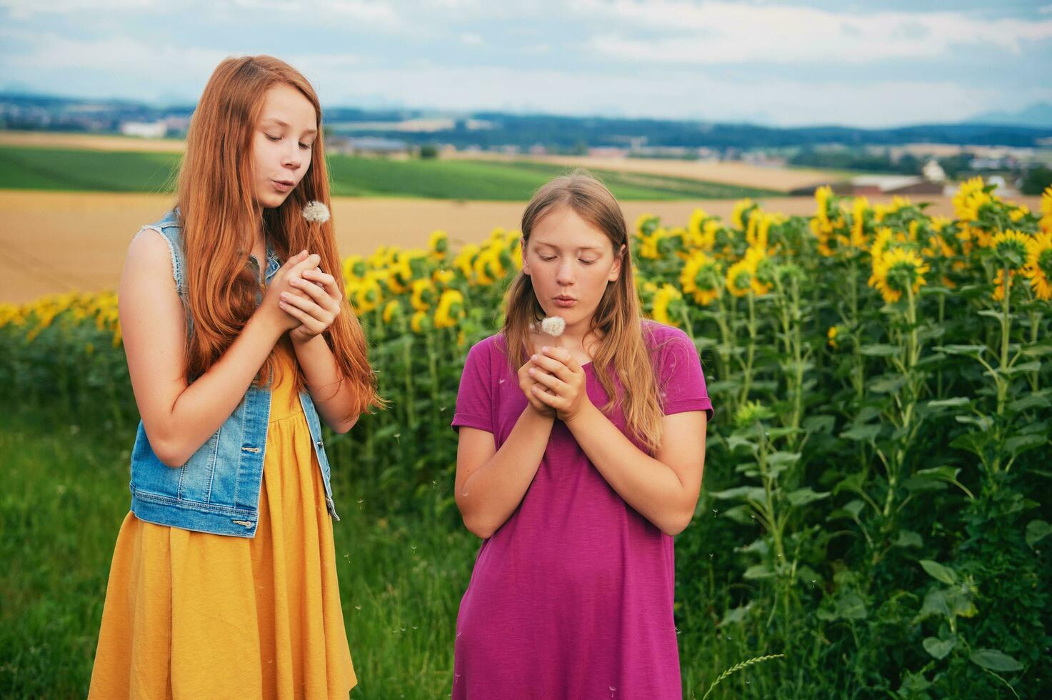 utomhus- porträtt av två Lycklig ung flickor spelar med maskrosor i landsbygden foto