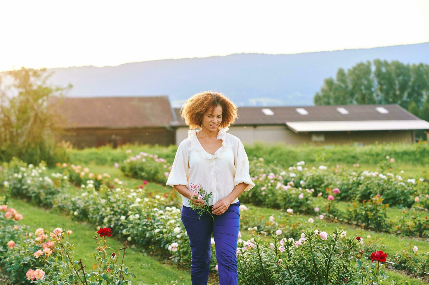 landsbygden livsstil, utomhus- porträtt av skön mitten ålder 50 - 55 år gammal kvinna njuter trevlig dag i blomma bruka trädgård foto