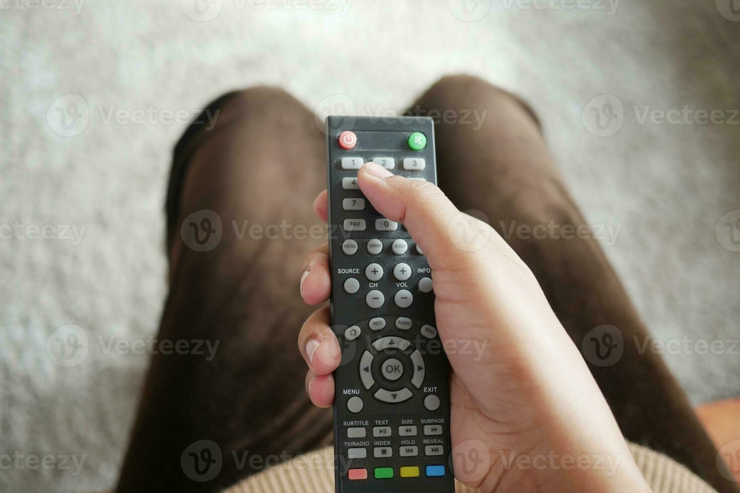 närbild av kvinnor hand som håller tv-fjärrkontroll. foto