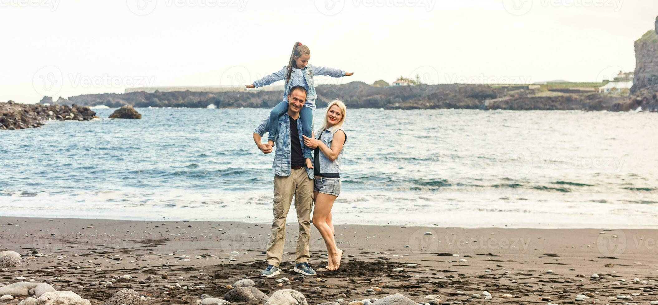 Lycklig familj stående på de strand på de gryning tid foto