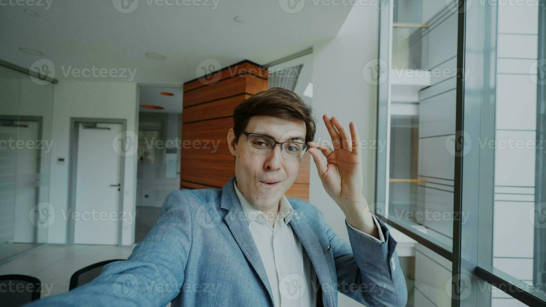 pOV av ung glad affärsman i glasögon tar en selfie Foto och ha roligt i modern kontor inomhus