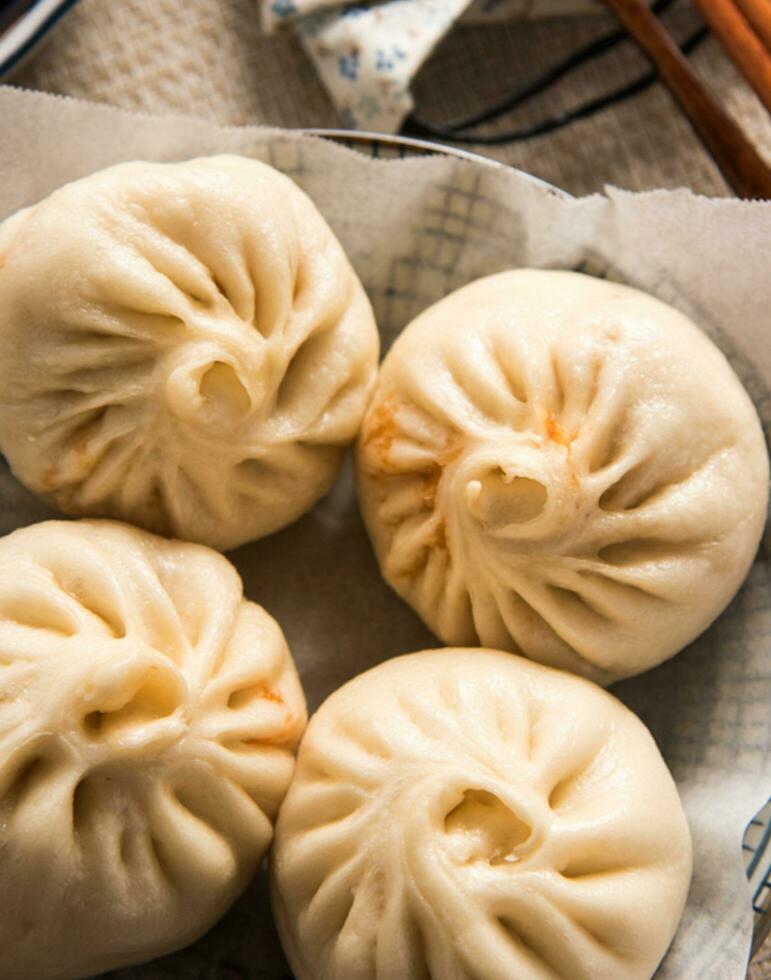 kinesisk mat, baozi är en traditionell delikatess i Kina, bröd mat fotografi så frestande, utsökt baozi, kinesisk ångad kött bulle är redo till äta på tjänande tallrik och ångkokare foto