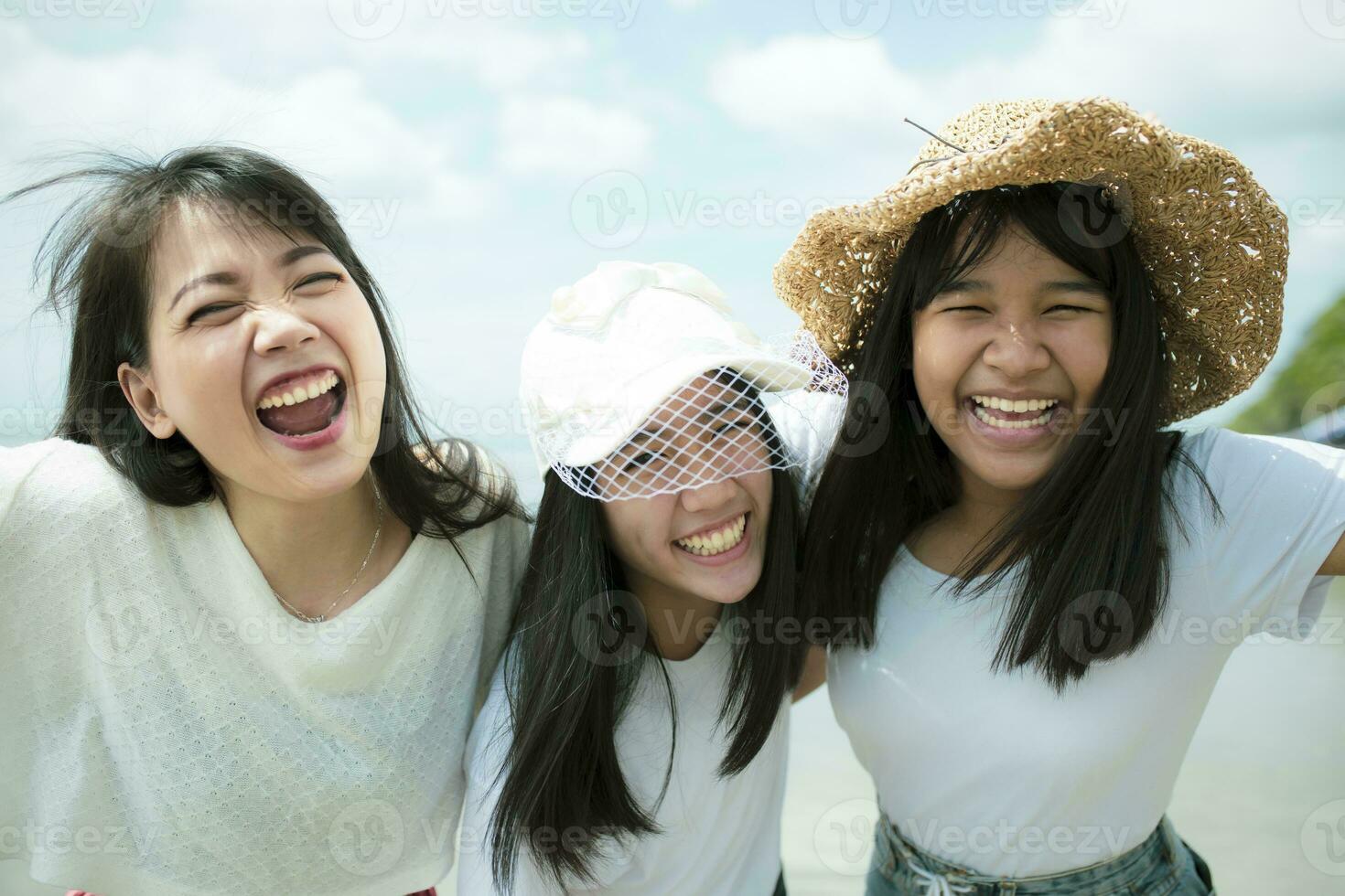 tre asiatisk yngre kvinna och tonåring Lycklig på hav strand foto