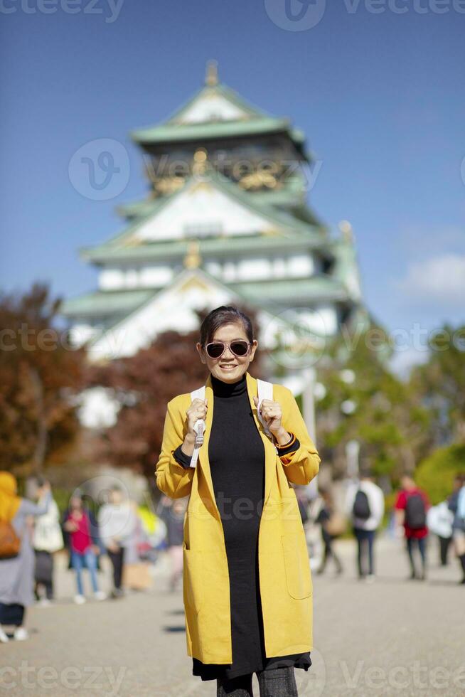 asiatisk kvinna turist tar en fotografera på osaka slott ett av mest populär reser destination i japan foto