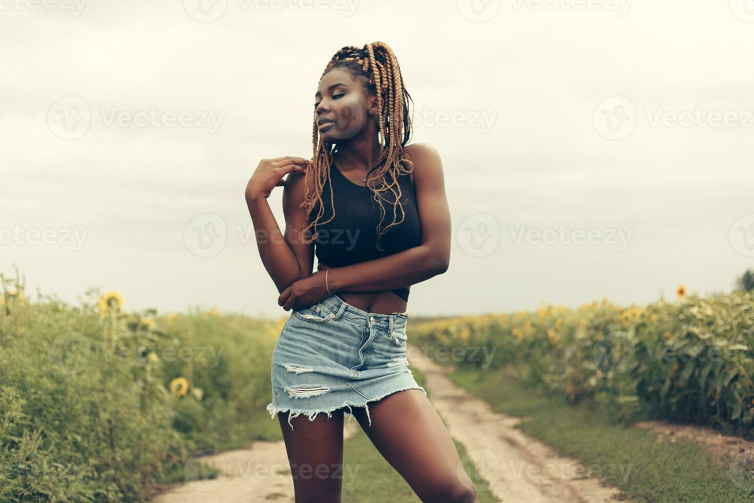 afrikansk amerikan flicka i en fält av gul blommor på solnedgång foto