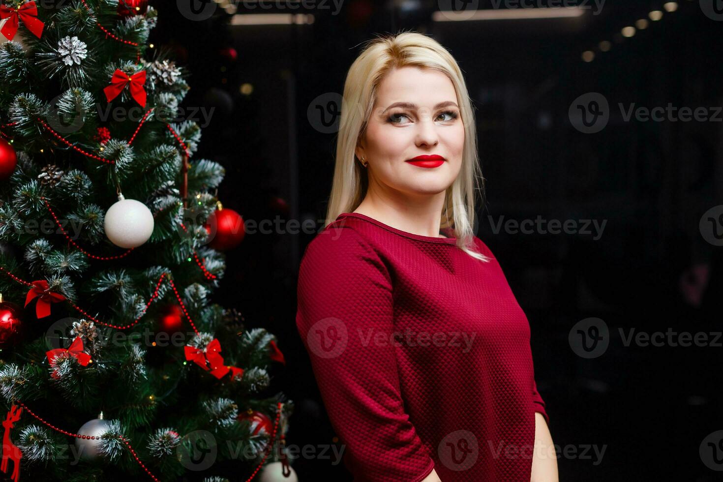 leende kvinna nära de jul träd. modern lyx flicka fira ny år. skön lyx trendig blond. foto