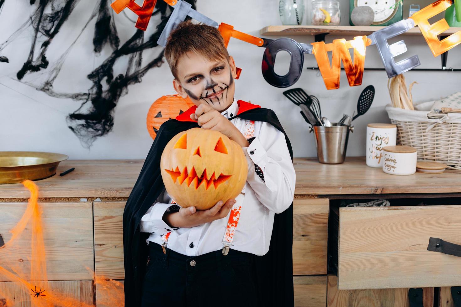 leende pojke som står i maskeradklänning som håller en pumpa - bild foto