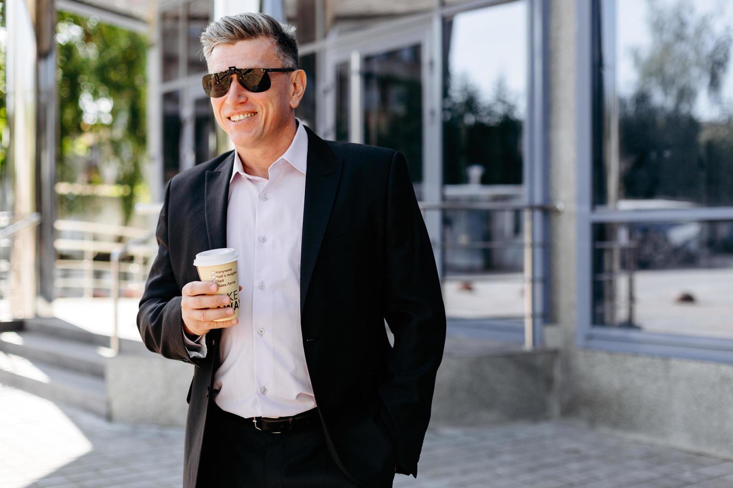 porträtt av senior affärsman som håller en kopp kaffe och ler. - bild foto