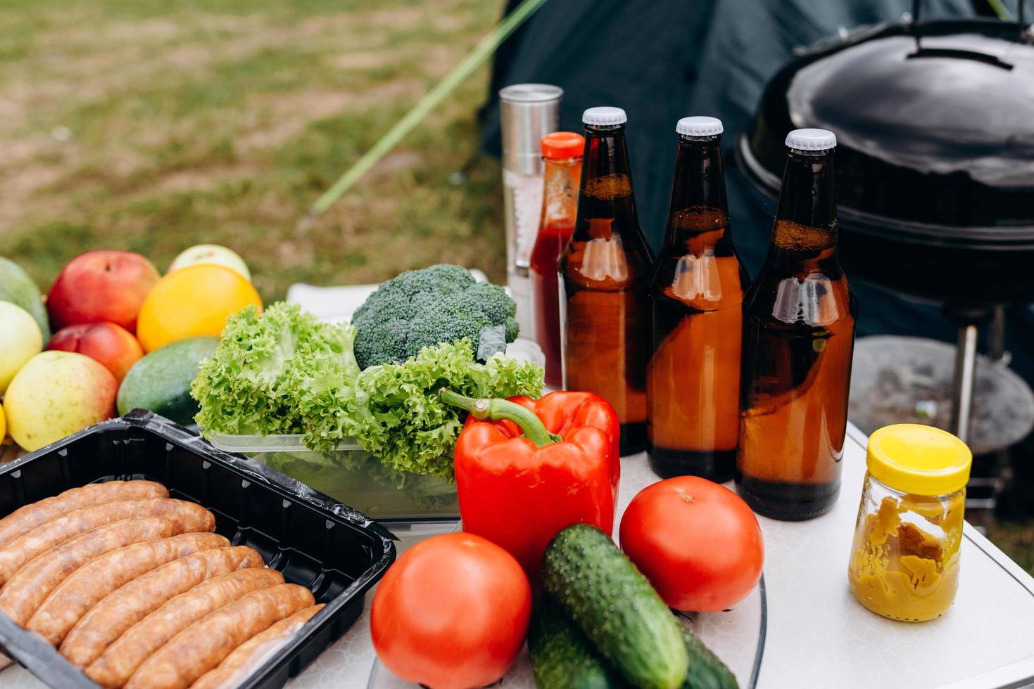 öl, korv och färska grönsaker på bordet utomhus. - bild foto