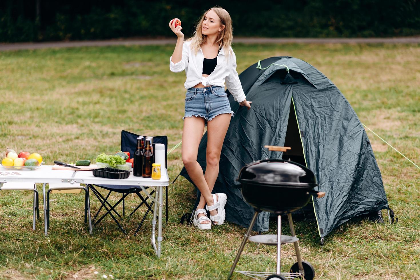 flicka som står på campingen med ett äpple och ler lekfullt foto