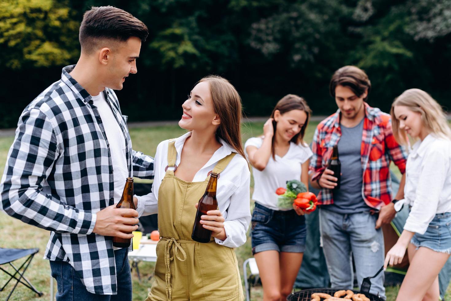 ett sällskap av vänner med en drink och mat har roligt på campingen. - bild foto