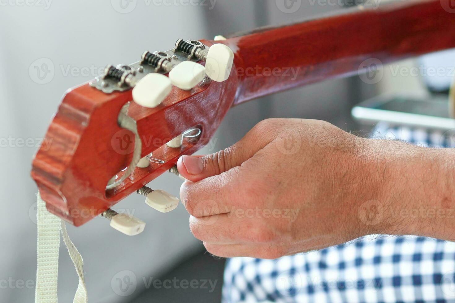 närbild av en mannens händer inställning en gitarr. foto