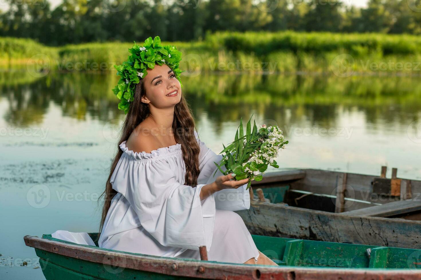 de nymf med lång mörk hår i en vit årgång klänning Sammanträde i en båt i de mitten av de flod. foto