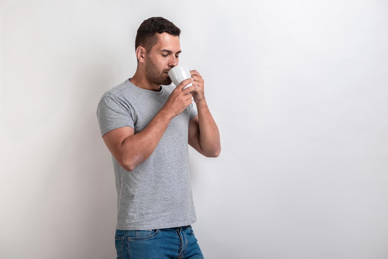 mannen står med en kopp morgontete eller kaffe och dricker det med nöje.- bild foto