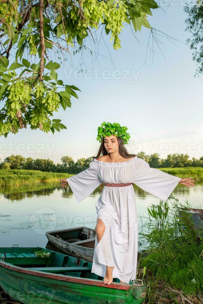 ung kvinna med blomma krans på henne huvud, avkopplande på båt på flod på solnedgång. begrepp av kvinna skönhet, resten i de by foto