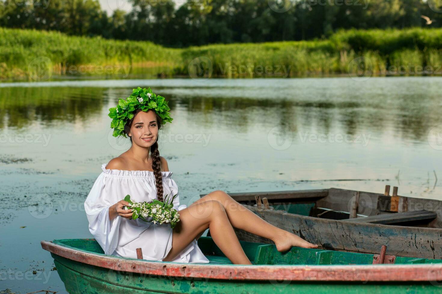 ung sexig kvinna på båt på solnedgång. de flicka har en blomma krans på henne huvud, avkopplande och segling på flod. fantasi konst fotografi. foto