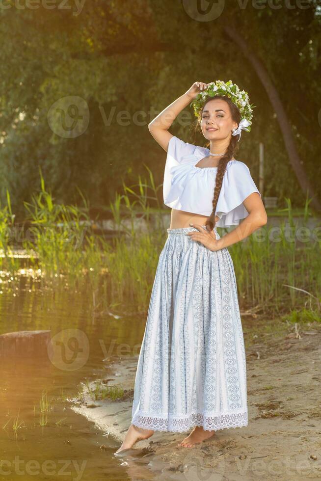 ung skön caucasian kvinna stående på de Bank av flod. traditionell landsbygden bild med flicka på förgrund och kopia Plats. foto