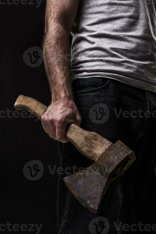 en man innehar ett yxa i hans händer mot på svart bakgrund foto