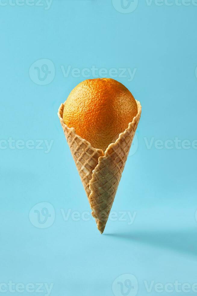 orange tycka om is grädde lögner i våffla kon på en ljus blå bakgrund. foto