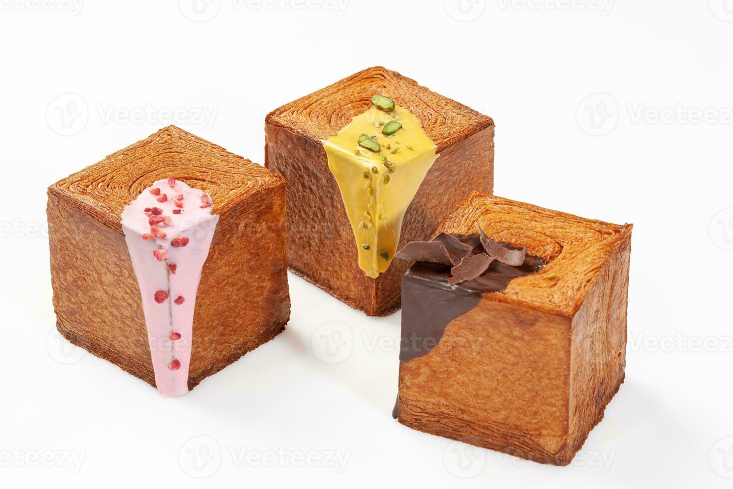 tre kub formad croissanter med krämig bär glasyr, pistasch sås och choklad ganache foto