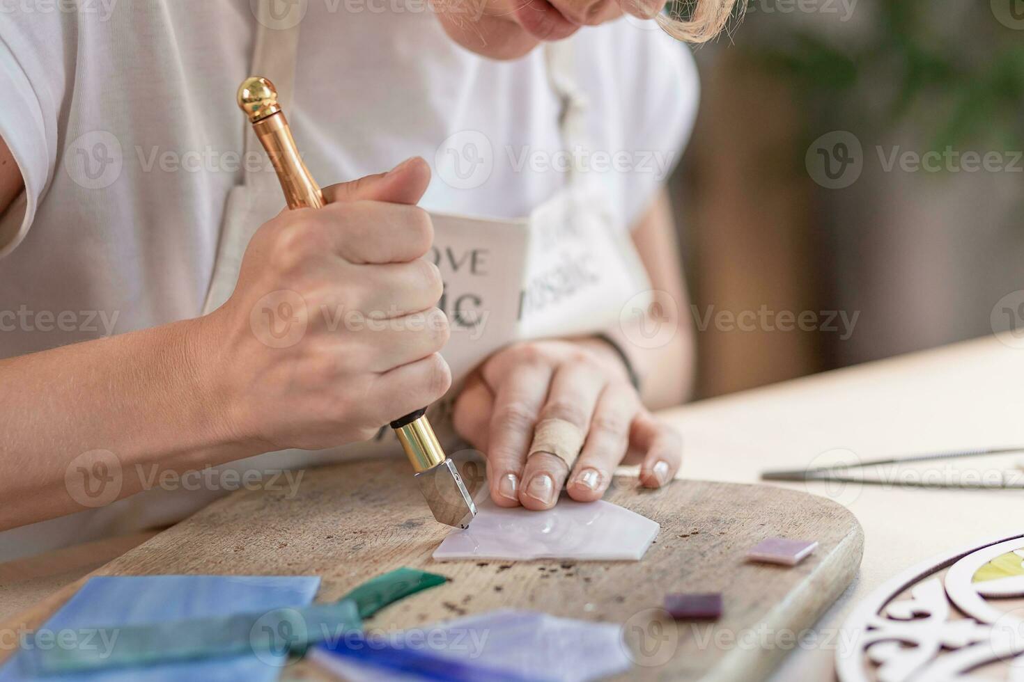 konstnär skärande ark av färgade glas in i små mosaik- rutor. närbild foto