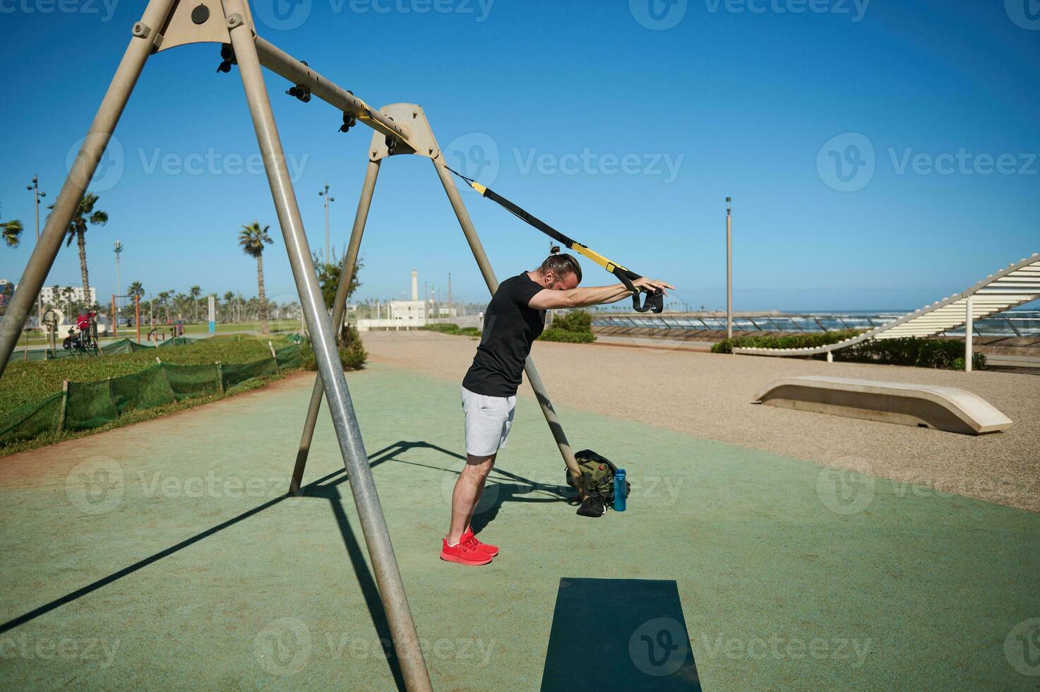 full längd porträtt av en sportsman arbetssätt ut utomhus, utför kroppsvikt träna med kondition remmar foto
