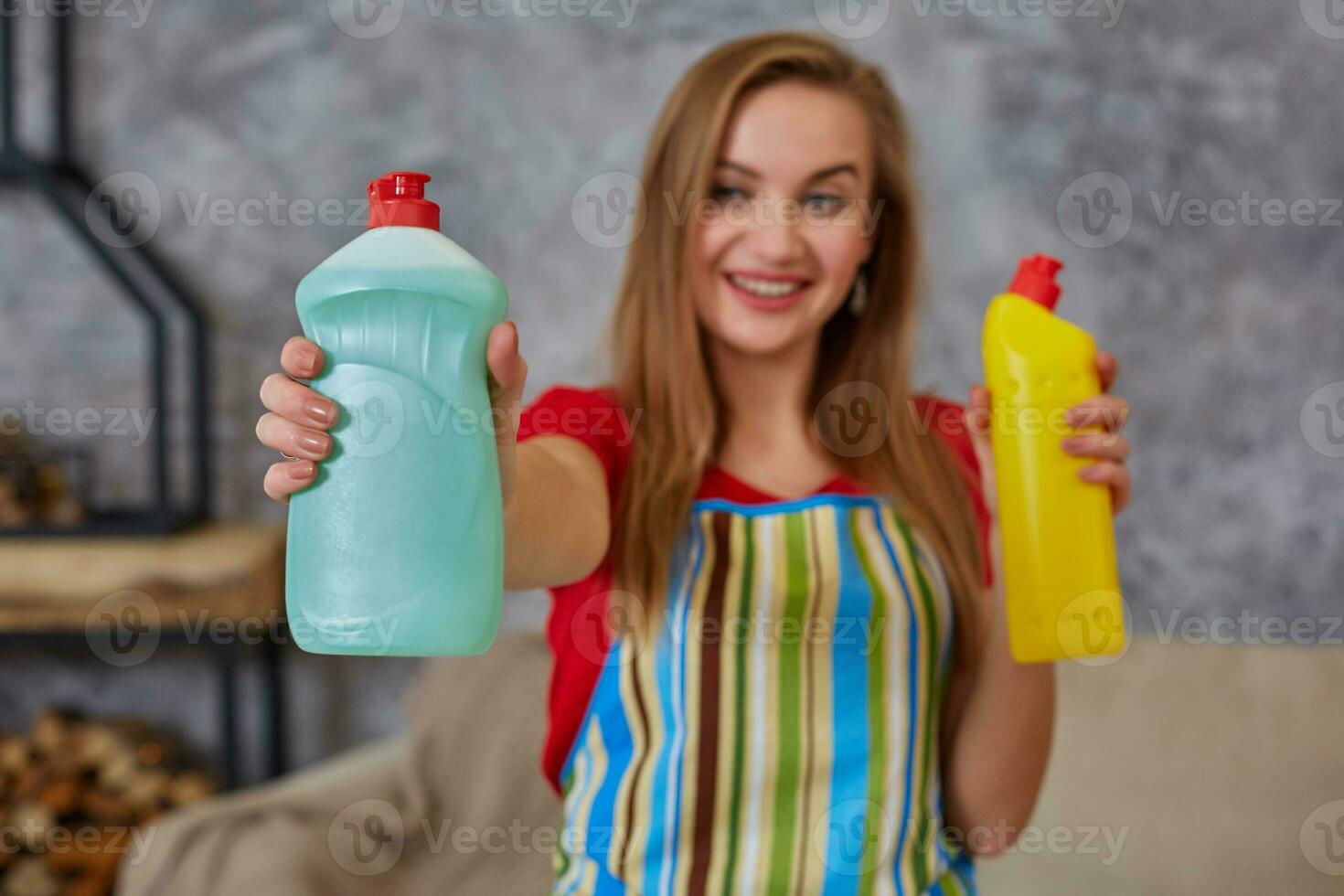 kvinna jämför två rengöringsmedel flaska på Hem rengöring i levande rum. Hem arbete. foto