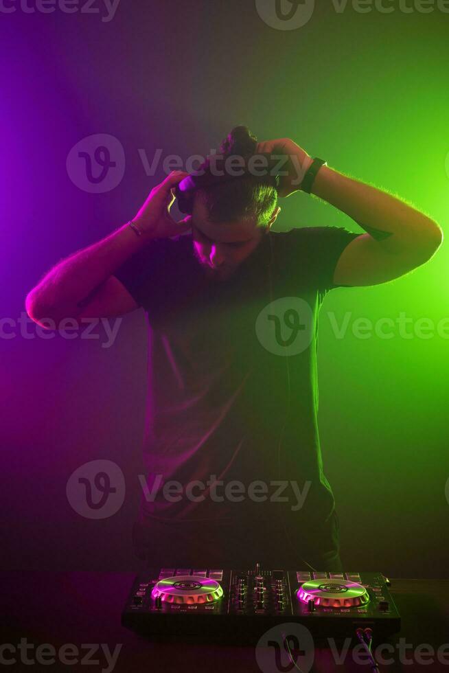 dj på arbete blandning ljud på henne däck på en fest eller natt klubb med färgrik rök ljus bakgrund foto