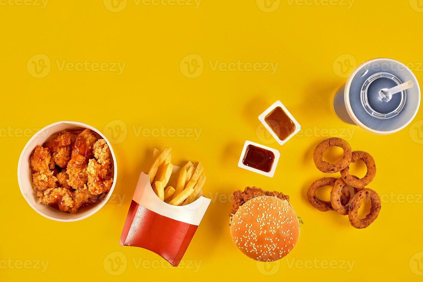 snabb mat maträtt topp se. franska pommes frites, hamburgare, majonnäs och ketchup såser på gul bakgrund. foto